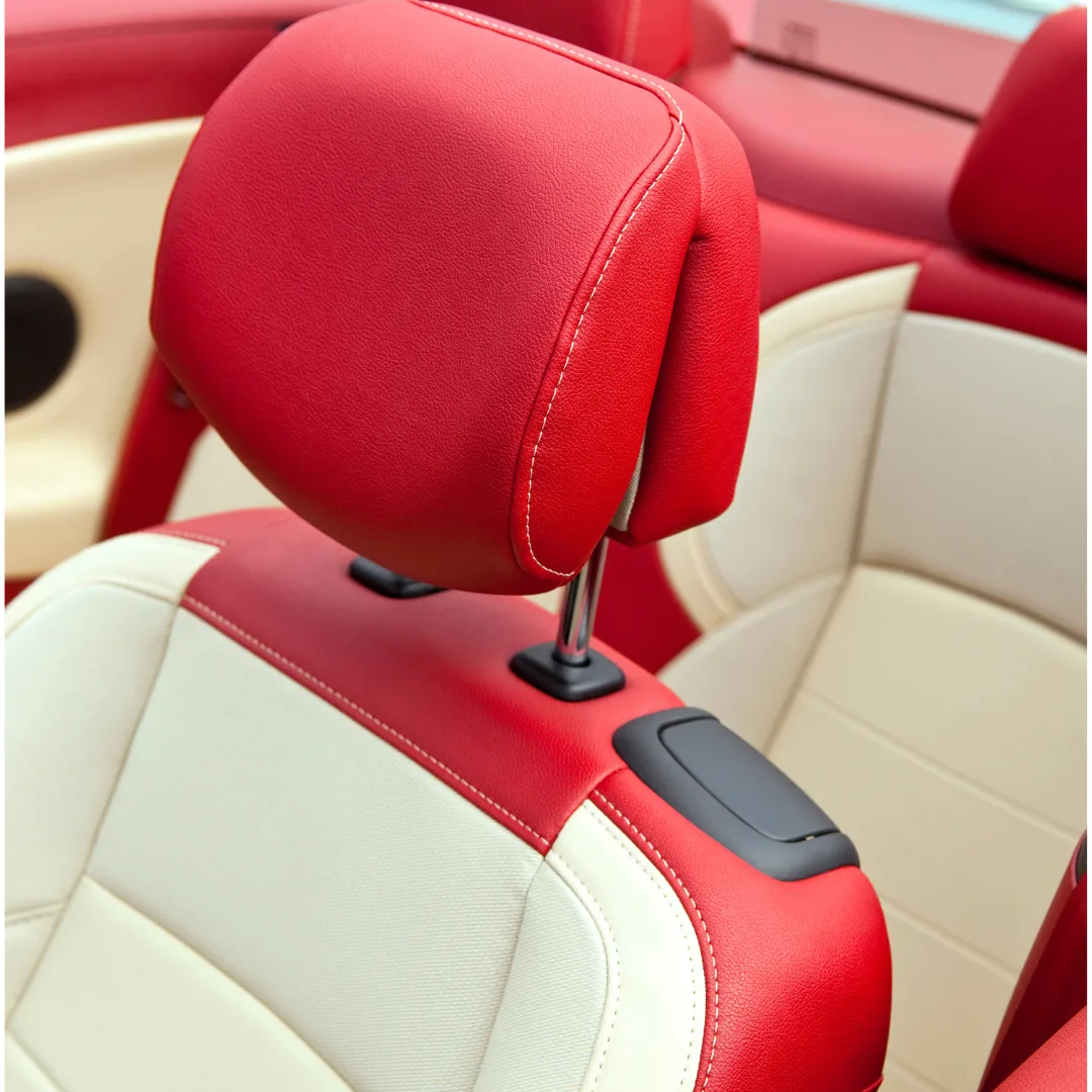 Red and beige car seat upholstery with a headrest in a convertible car interior.